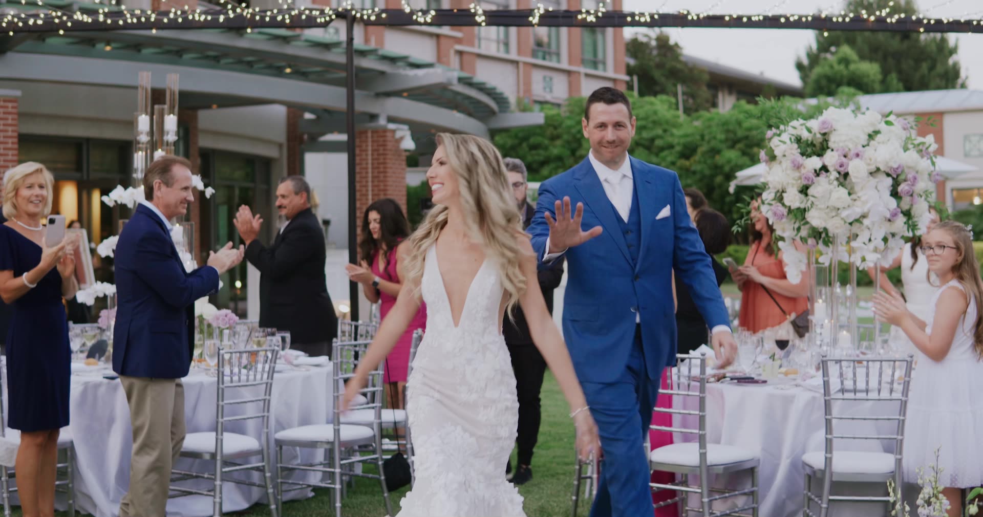 Alano and Alla entering their reception through applauding guests under string lights at Four Seasons Westlake Village