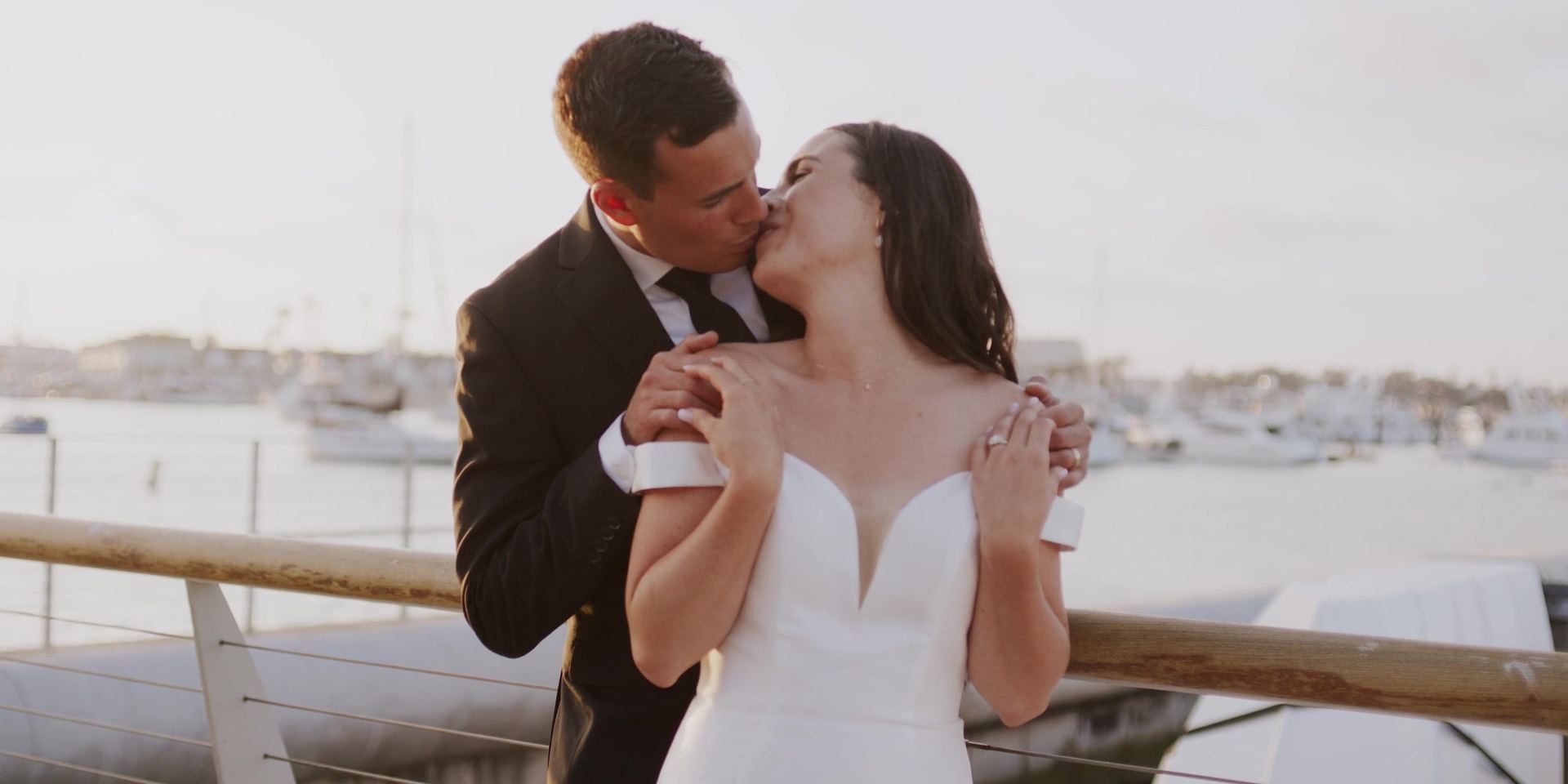Alex kissing Anna at the rail, the harbour behind them.
