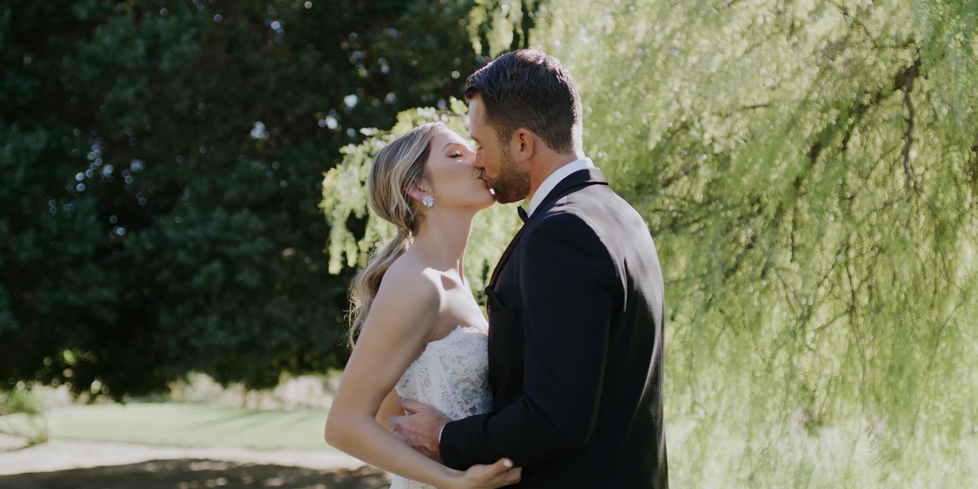 Andrew and Angelique kissing beneath the willow on the lawn at Old Polo Estate