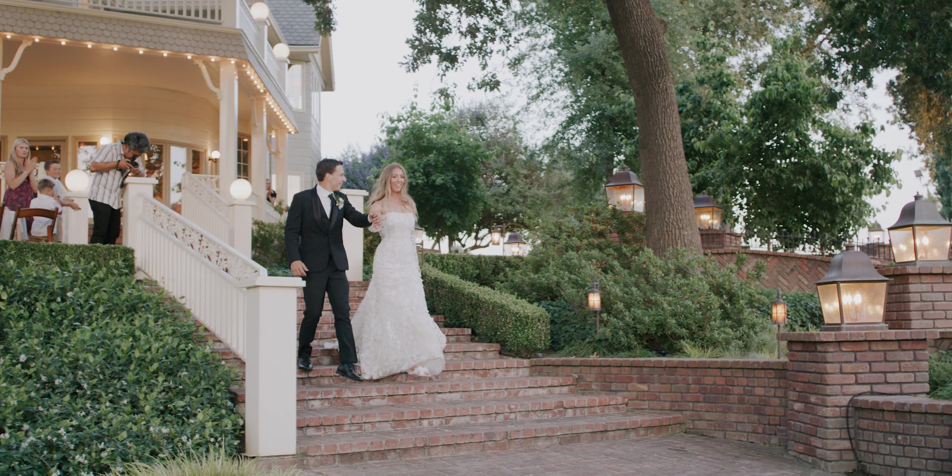 Anna and Jett coming down the steps at dusk beneath string lights in Kingsburg