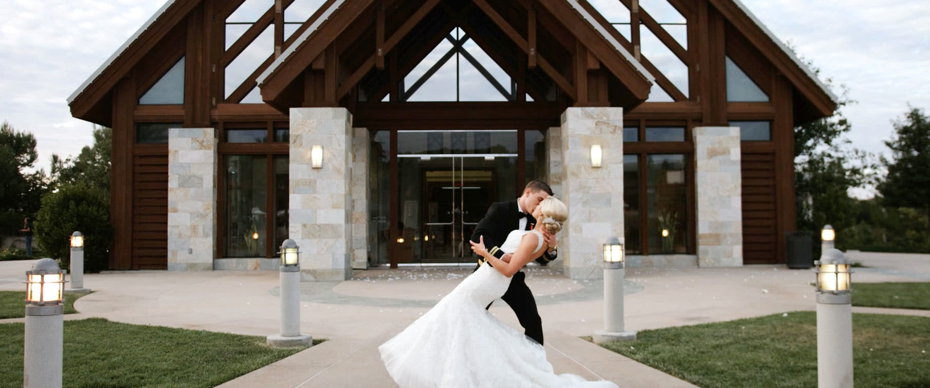 Andrew dipping Kendal for a kiss on the plaza in front of the timber entry of Mariners Church at dusk