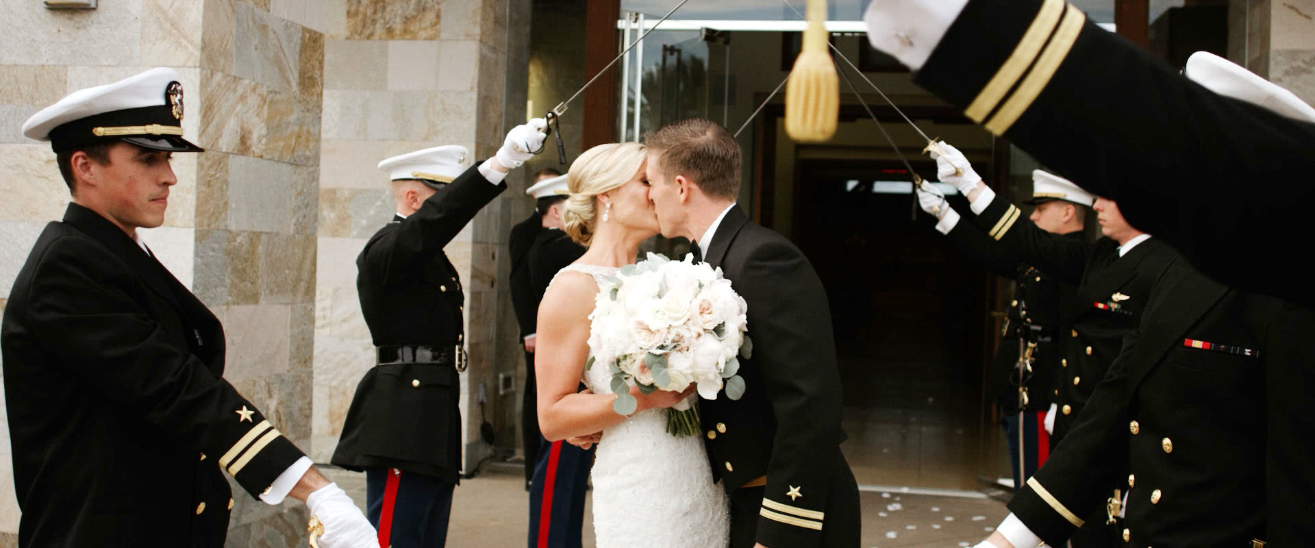 Navy officers raising a sword arch on the plaza outside Mariners Church as the bride and groom kiss beneath it