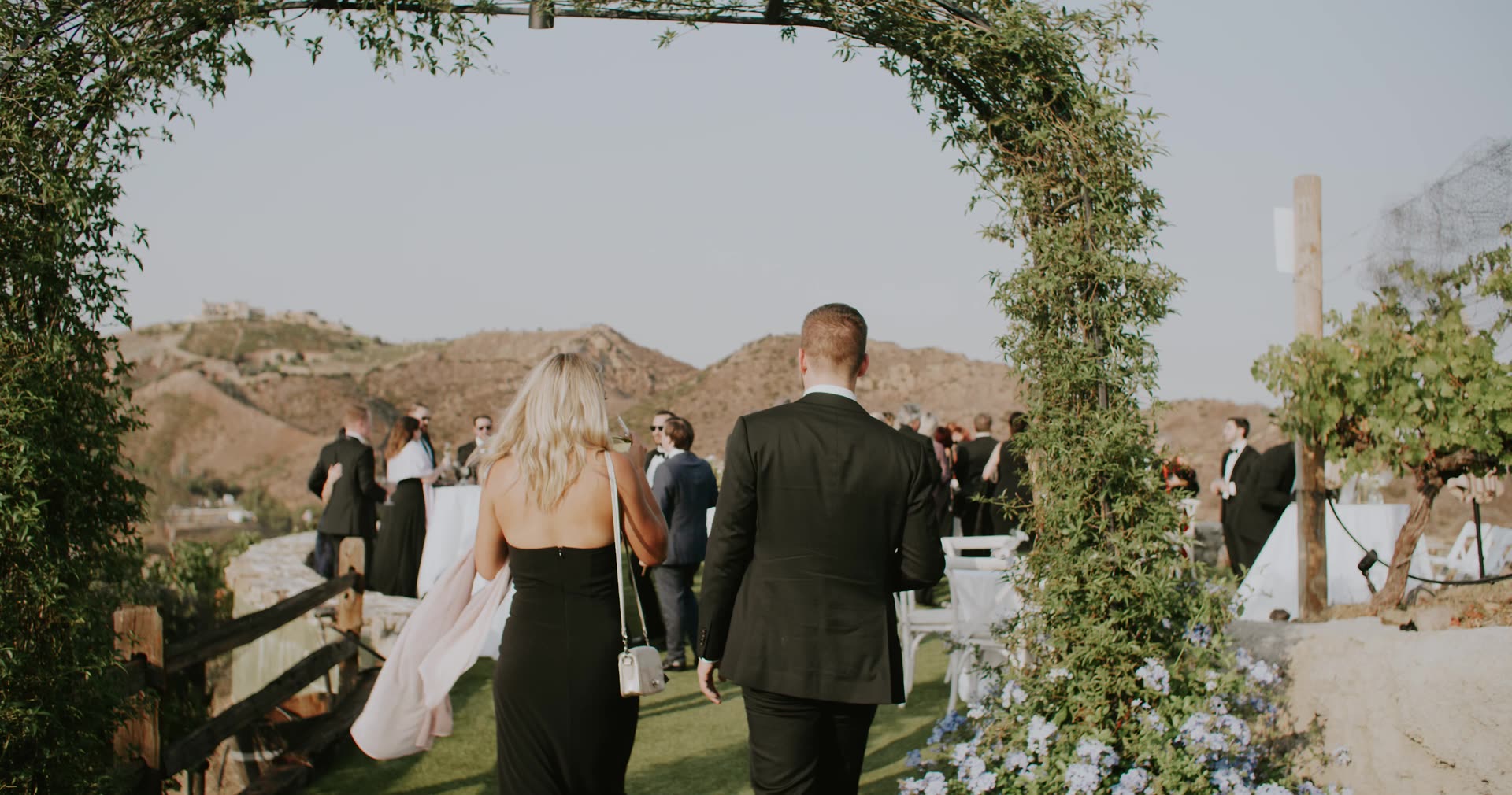 Alex and Leah walking back down the aisle through the arch at Cielo Farms, mountains beyond