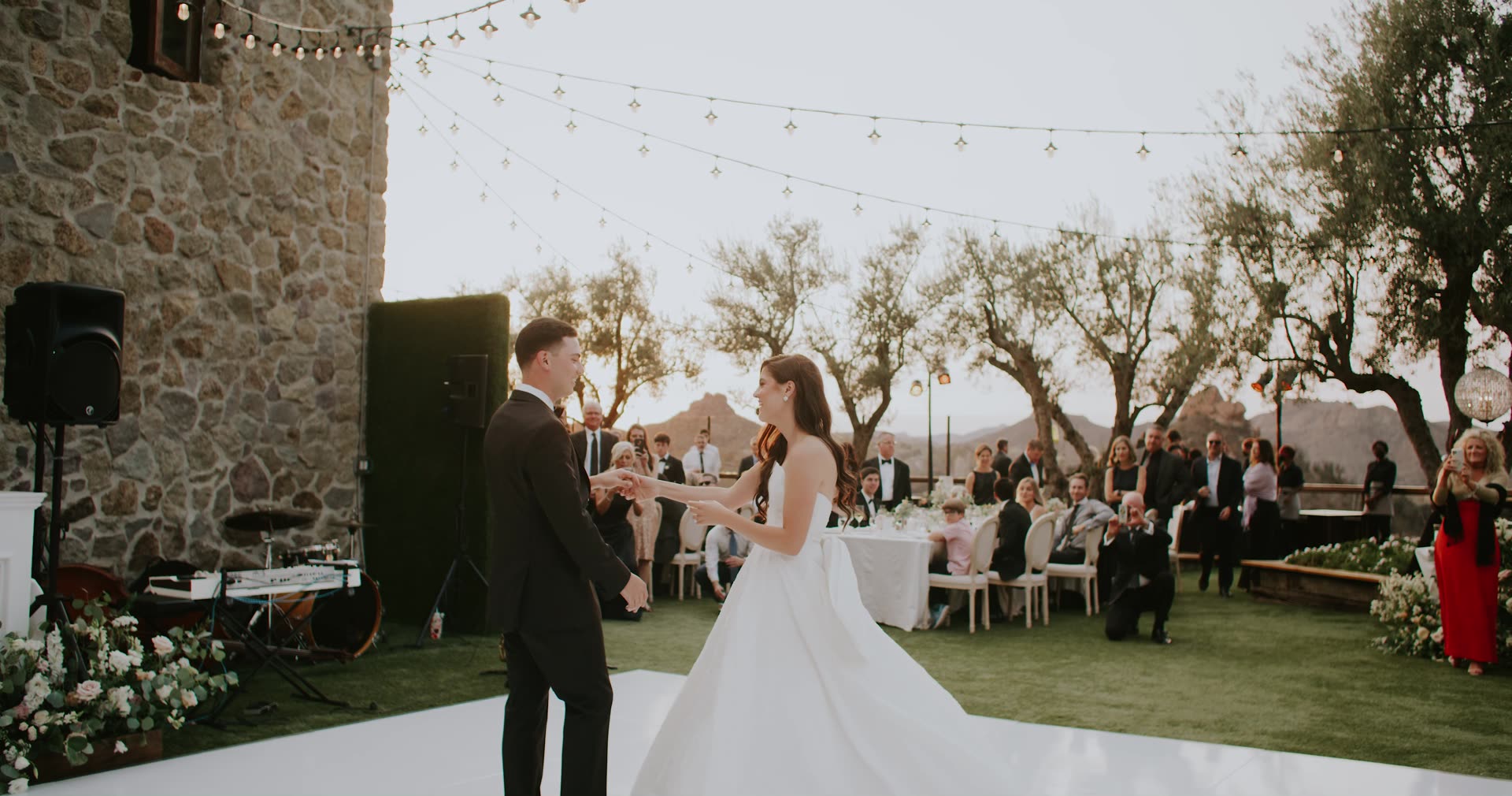Alex and Leah during their first dance under string lights among the olive trees at Cielo Farms