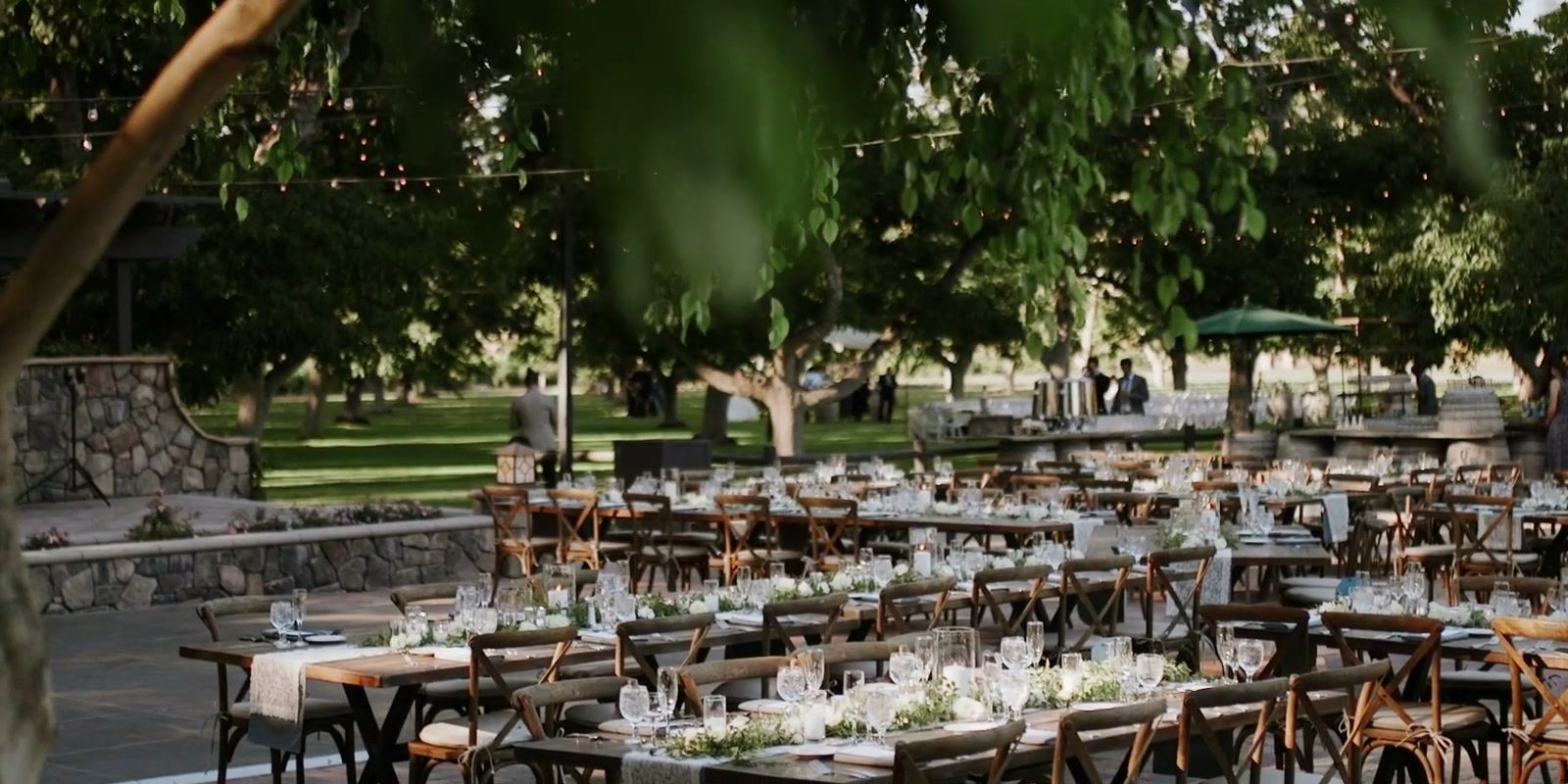 Long dinner tables set beneath the walnut trees beside a stone-edged dance floor.