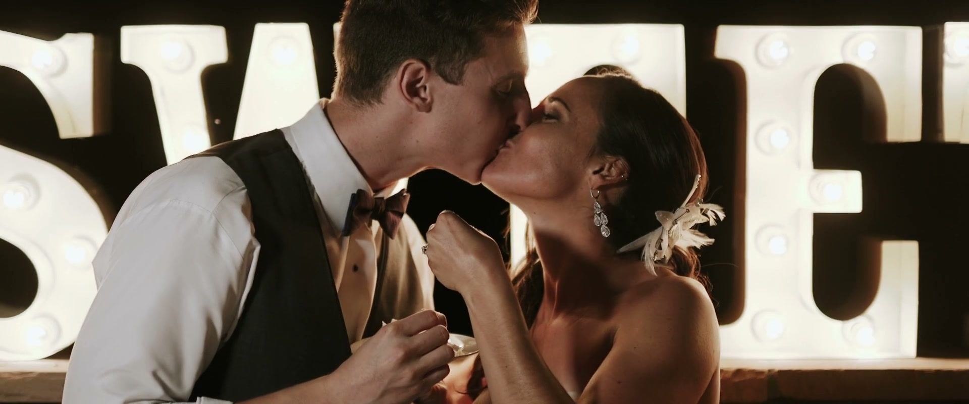 Alex and Lindsay kissing in front of lit marquee letters.