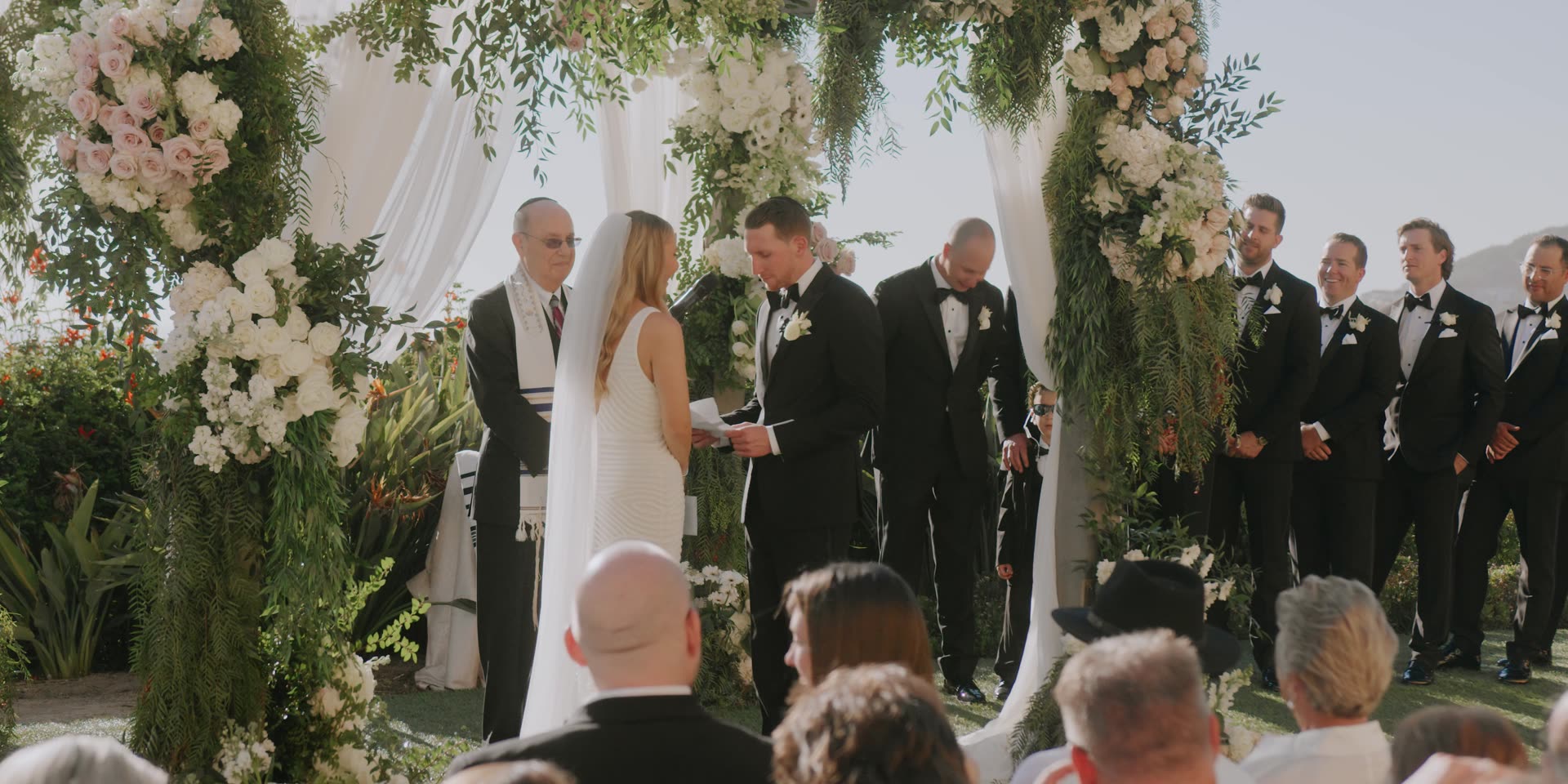 Adam and Laura at the altar under a floral arch on the oceanfront lawn at The Ritz-Carlton, Laguna Niguel