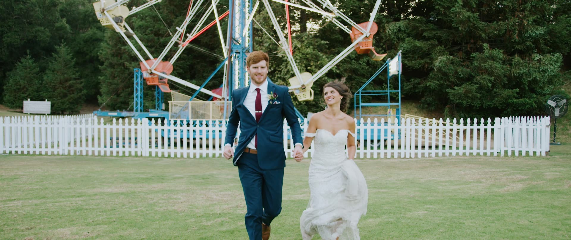 Andrew and Martha walking hand in hand past the Ferris wheel at Calamigos Ranch