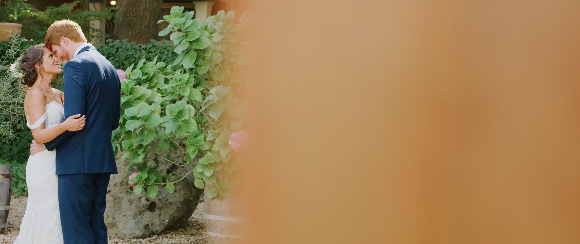 Andrew and Martha kissing beside the greenery at Calamigos Ranch