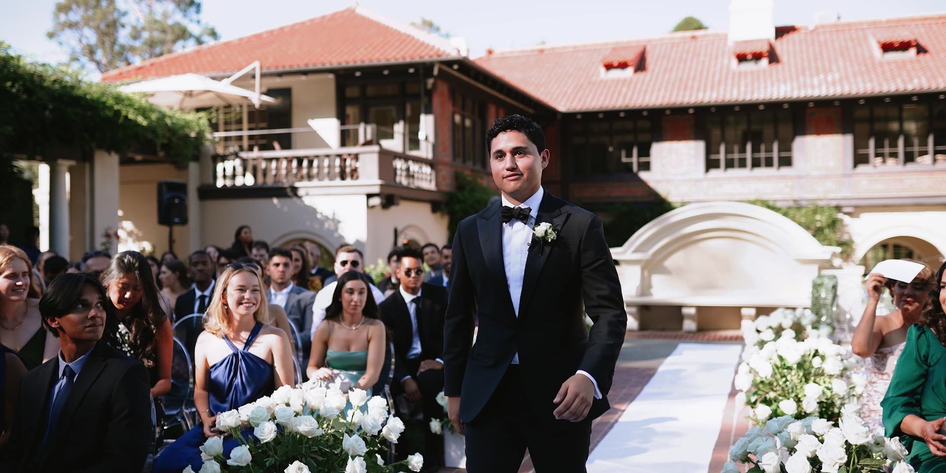 Antonio walking the aisle with the villa behind him at Villa Montalvo