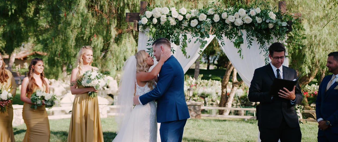 Brandon and Erin's first kiss under the rose arch at Lake Oak Meadows