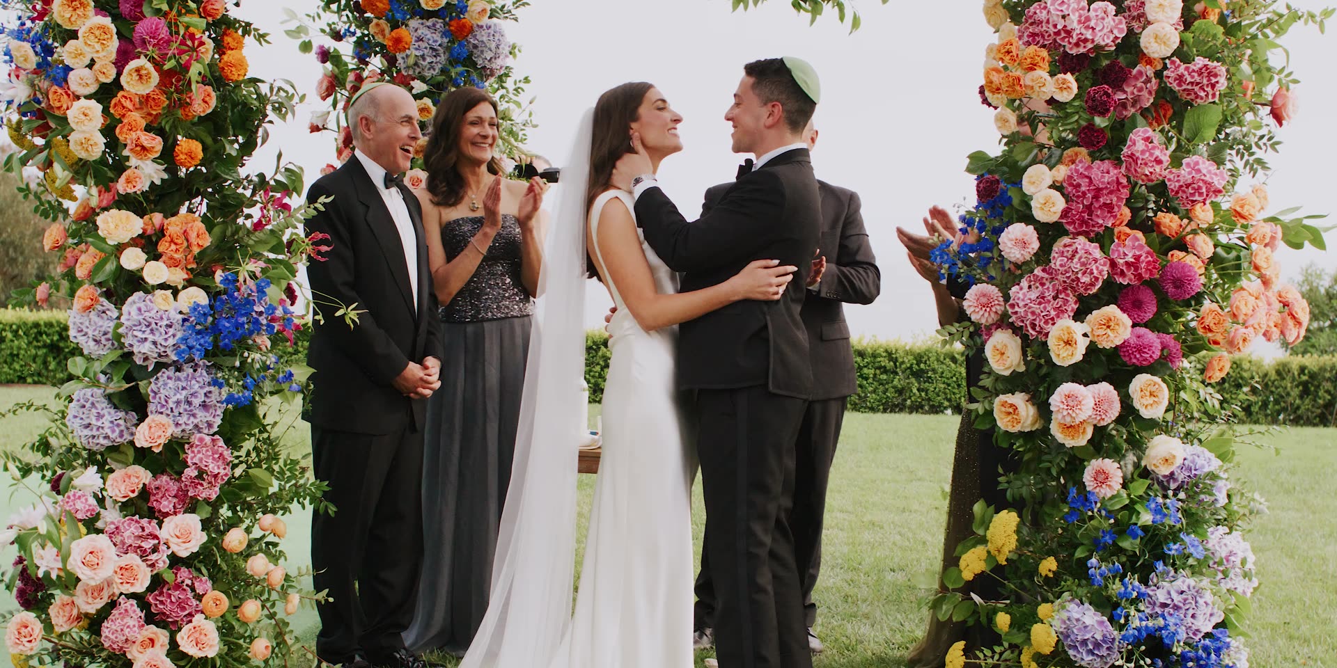 Brandon and Julie's ceremony beneath a arch of bright summer flowers in Carpinteria