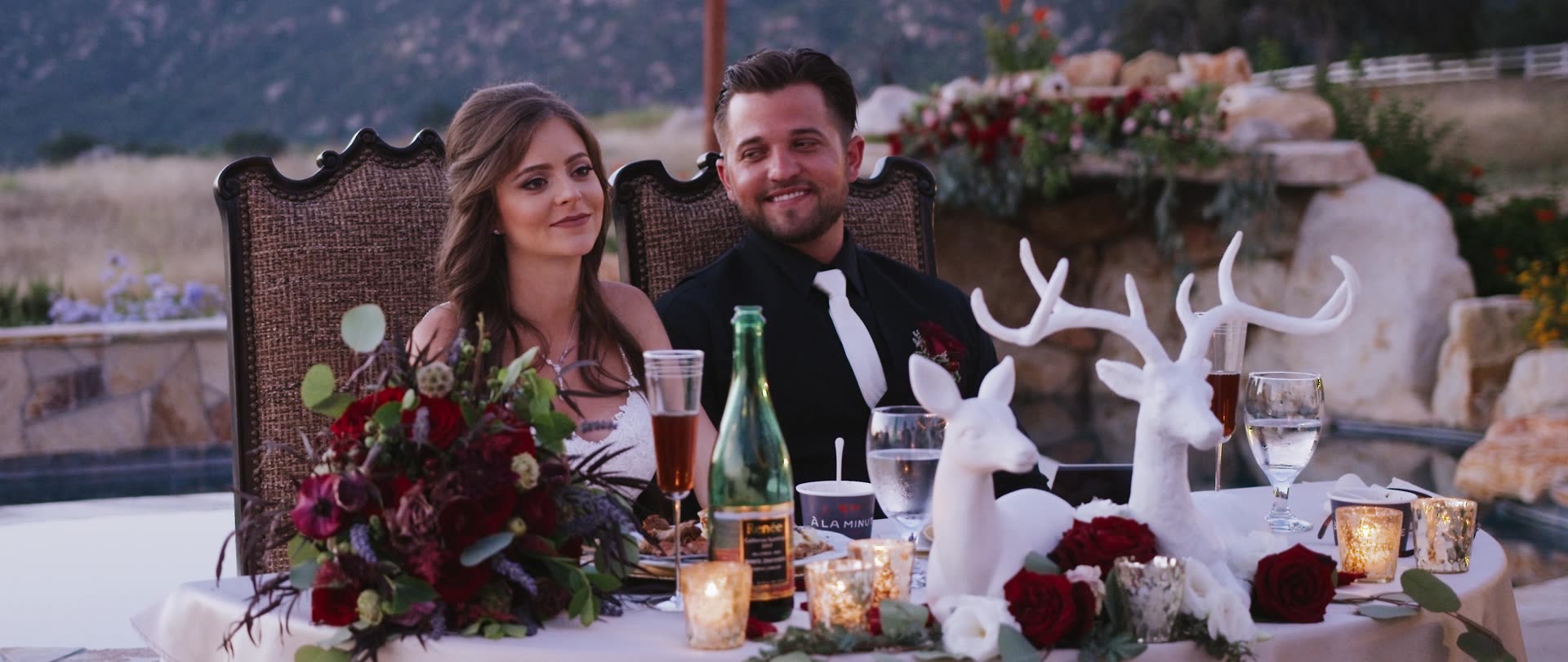 The sweetheart table set with deep red florals and candlelight in Murrieta