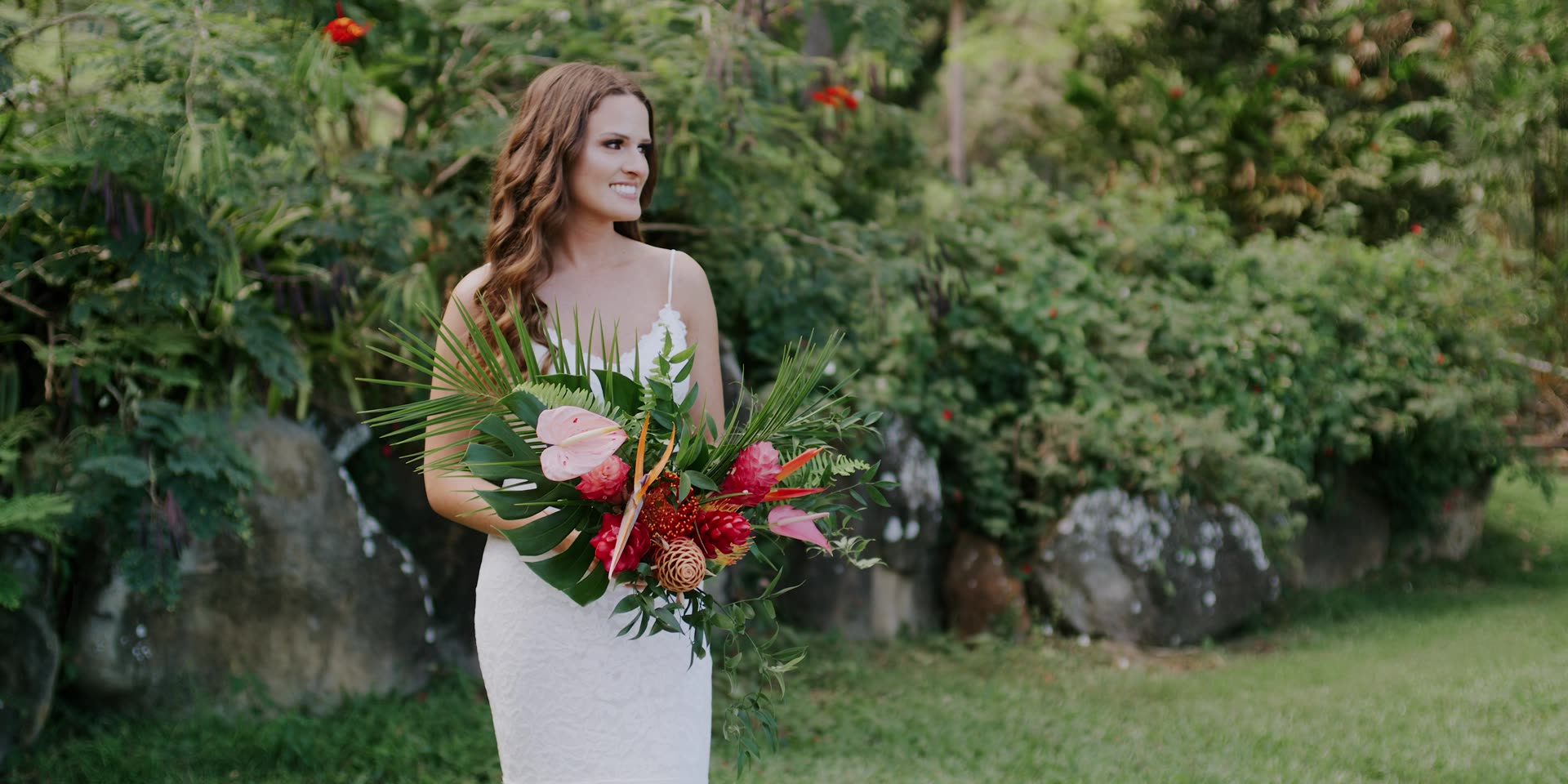 Bryn with a tropical bouquet of anthurium and protea in the gardens at Kualoa Ranch