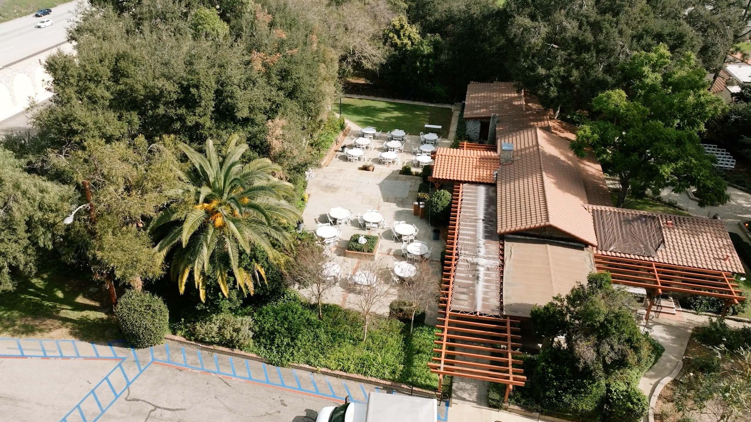 Hidden Oaks Retreat Center from above, reception tables on the terrace beside the tiled roofs and mature trees