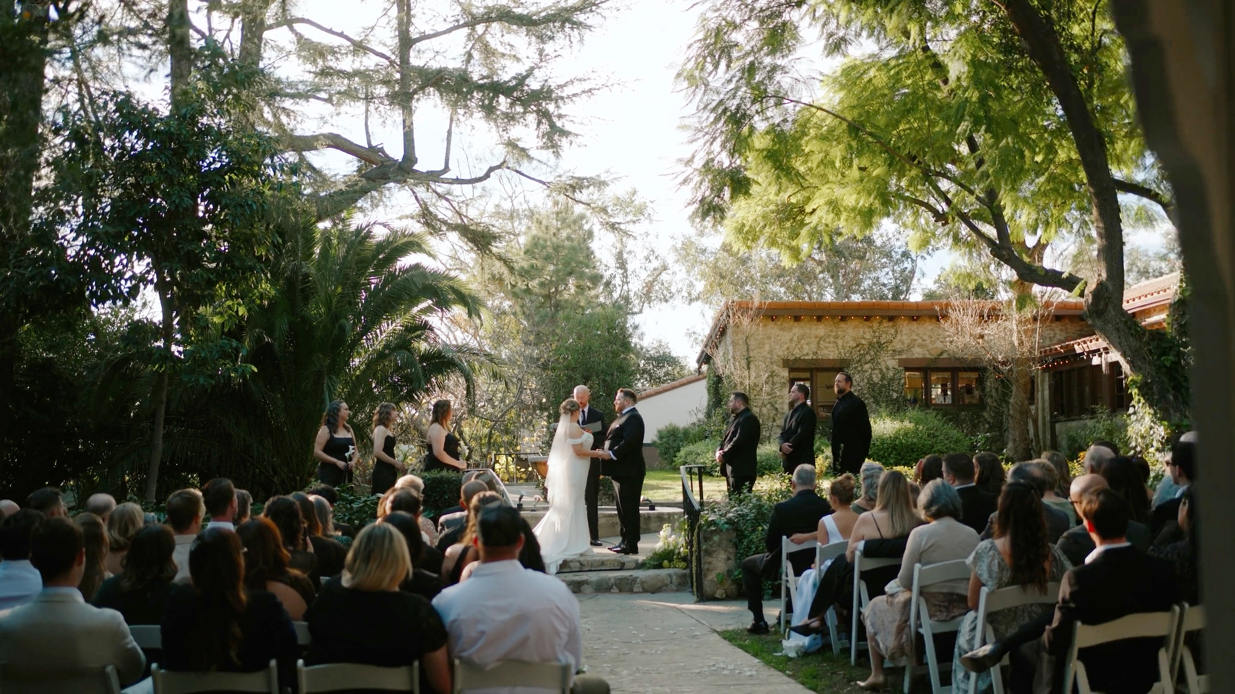 Chris and Emily's ceremony on the lawn under the oaks at Hidden Oaks Retreat Center, guests seated in white chairs
