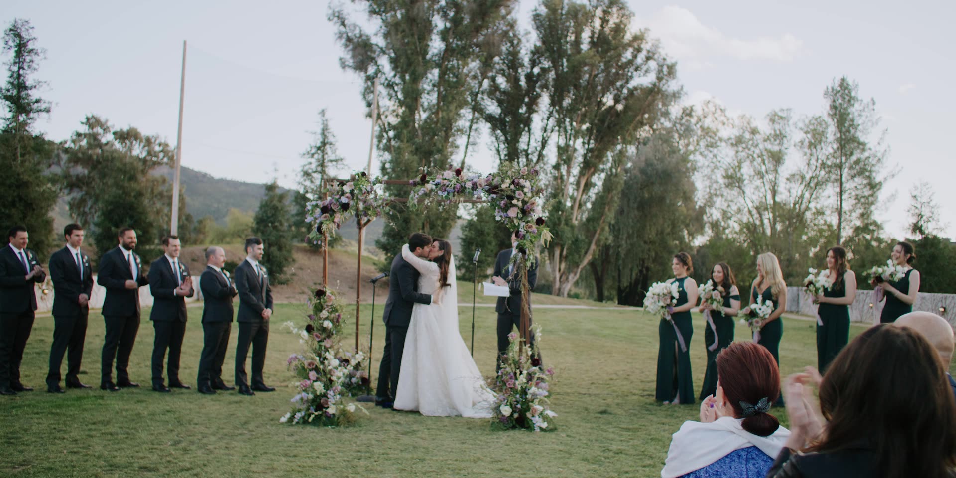 The ceremony with their wedding party and the mountains behind at Ojai Valley Inn