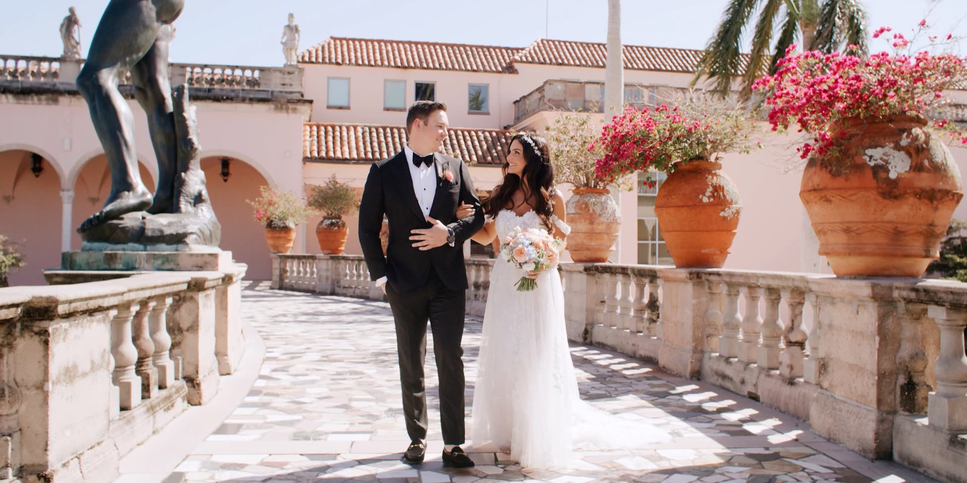 Bride and groom on the Ringling Museum courtyard terrace in Sarasota, bougainvillea and terracotta urns beside the bronze statuary