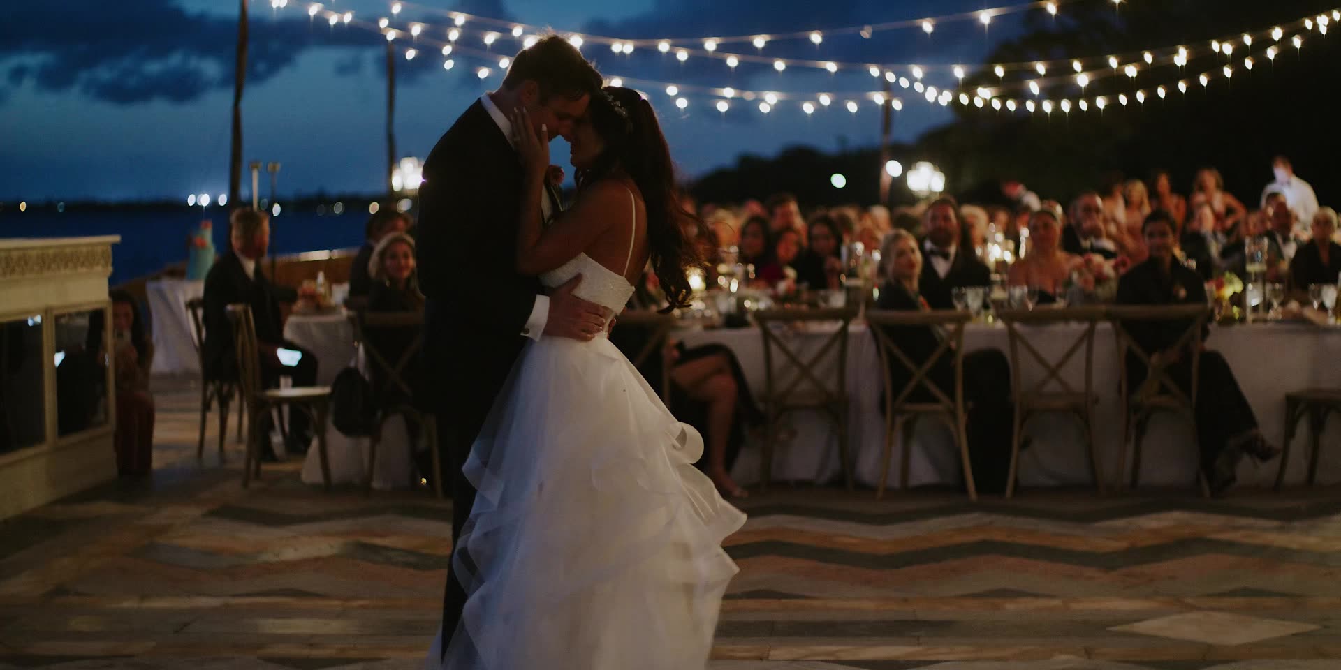 Cody and Lauren's first dance under string lights beside the water in Sarasota