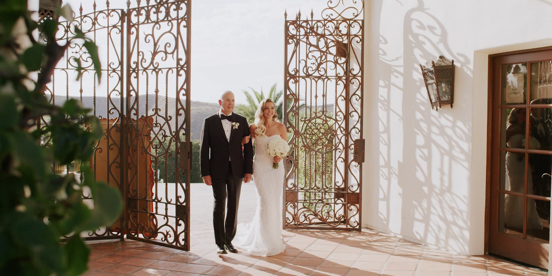 The bride entering through the ornate iron gates at Hummingbird Nest Ranch