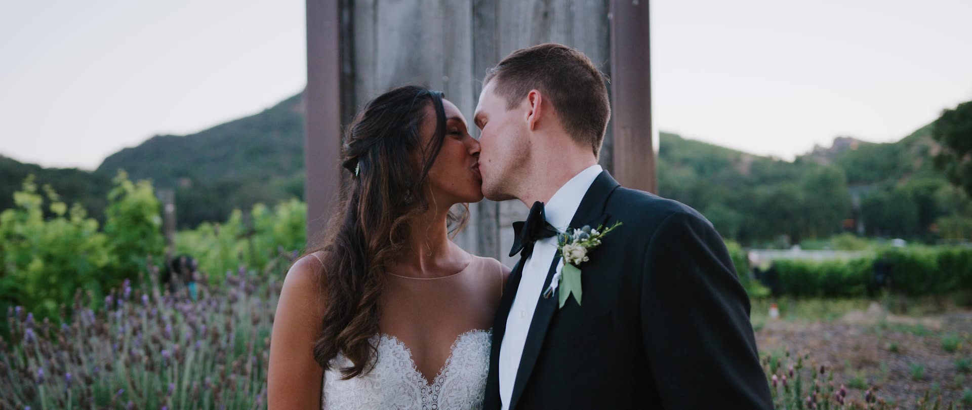 David and Lauren kissing among the lavender with the Malibu hills behind at Saddlerock Ranch