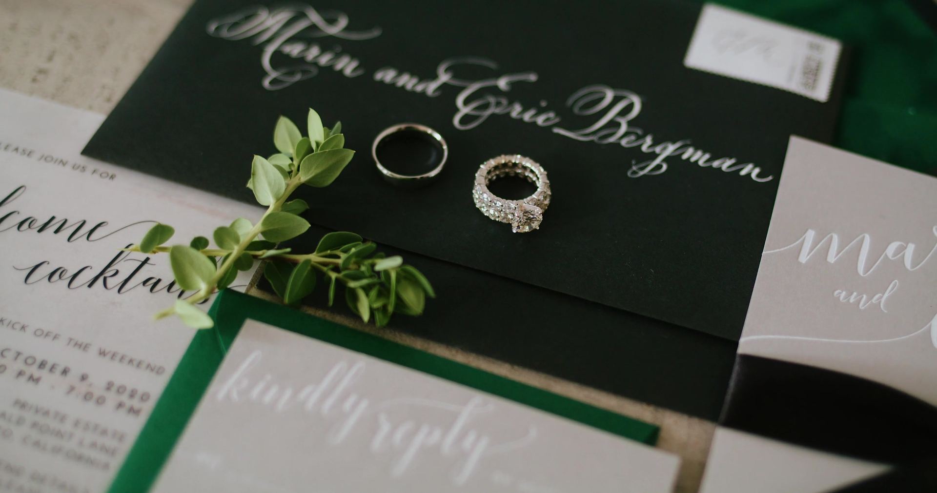 The invitation suite in black and green, laid out with both rings.