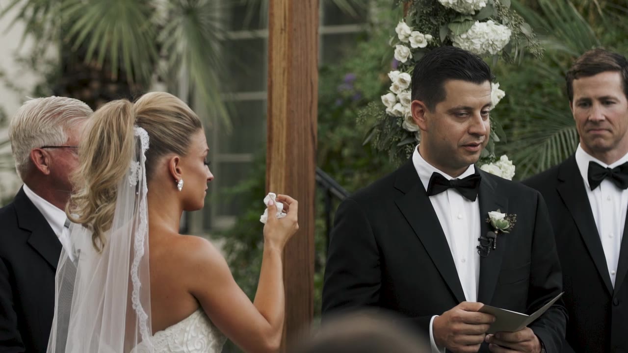Ellen and Sandro exchanging vows under the floral arch at the Colony Palms Hotel