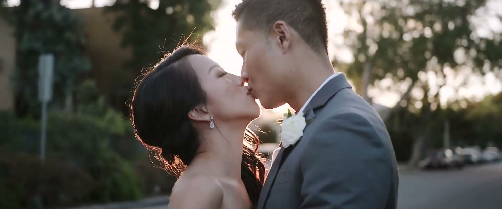 Andrea and Gene kissing in low golden light on a tree-lined street