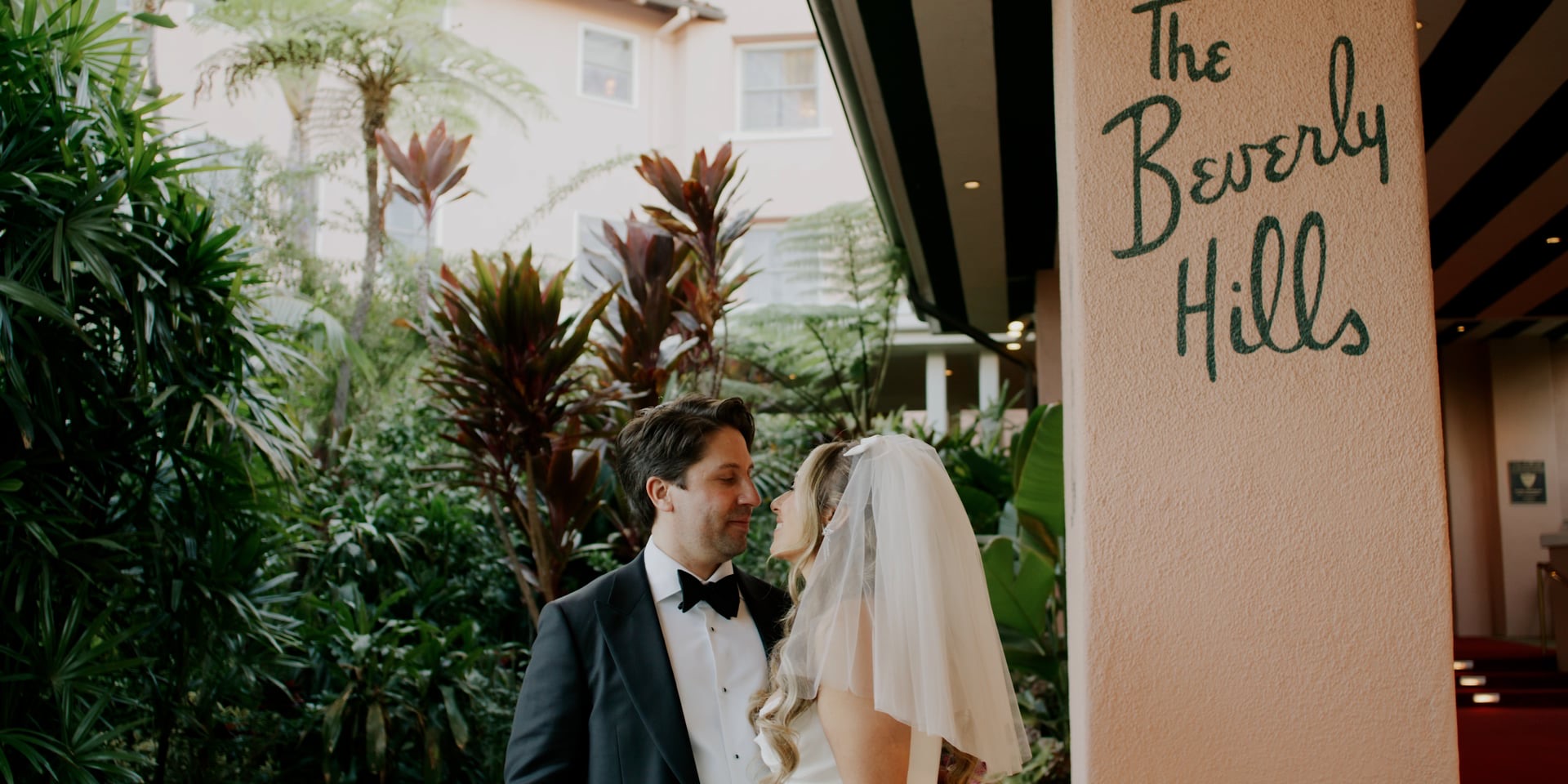 Ben and Roxy beside the iconic green script sign at The Beverly Hills Hotel