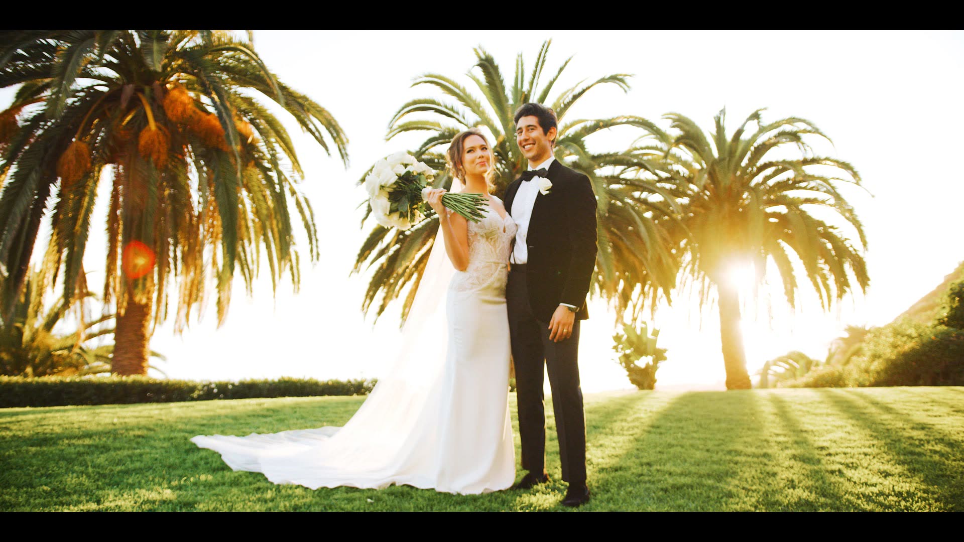 Colin and Michele standing between the palms on the lawn at Bel-Air Bay Club with the sun low behind them
