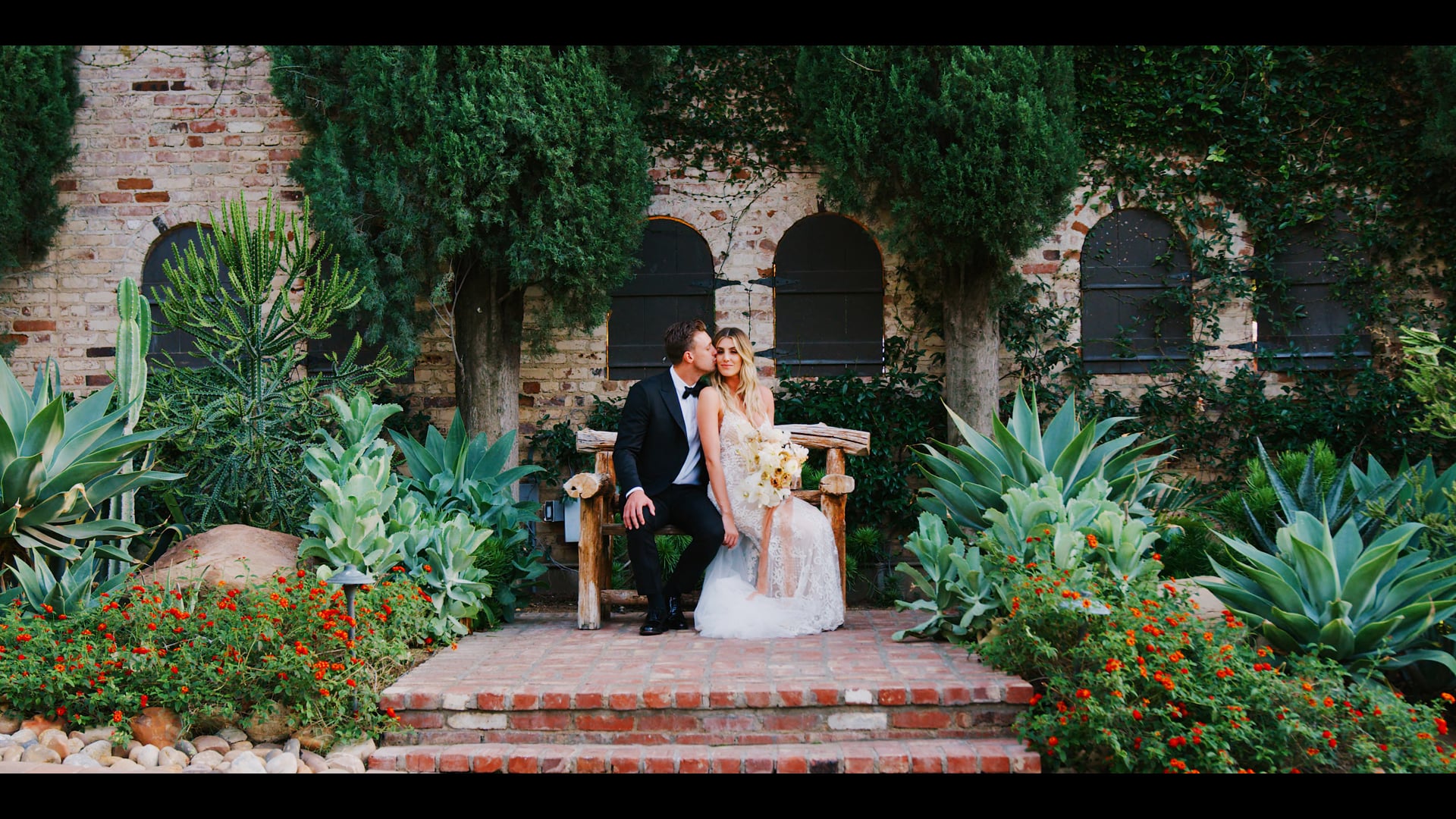 Daniel and Alexis on the brick steps beneath the arched stonework at Hummingbird Nest Ranch