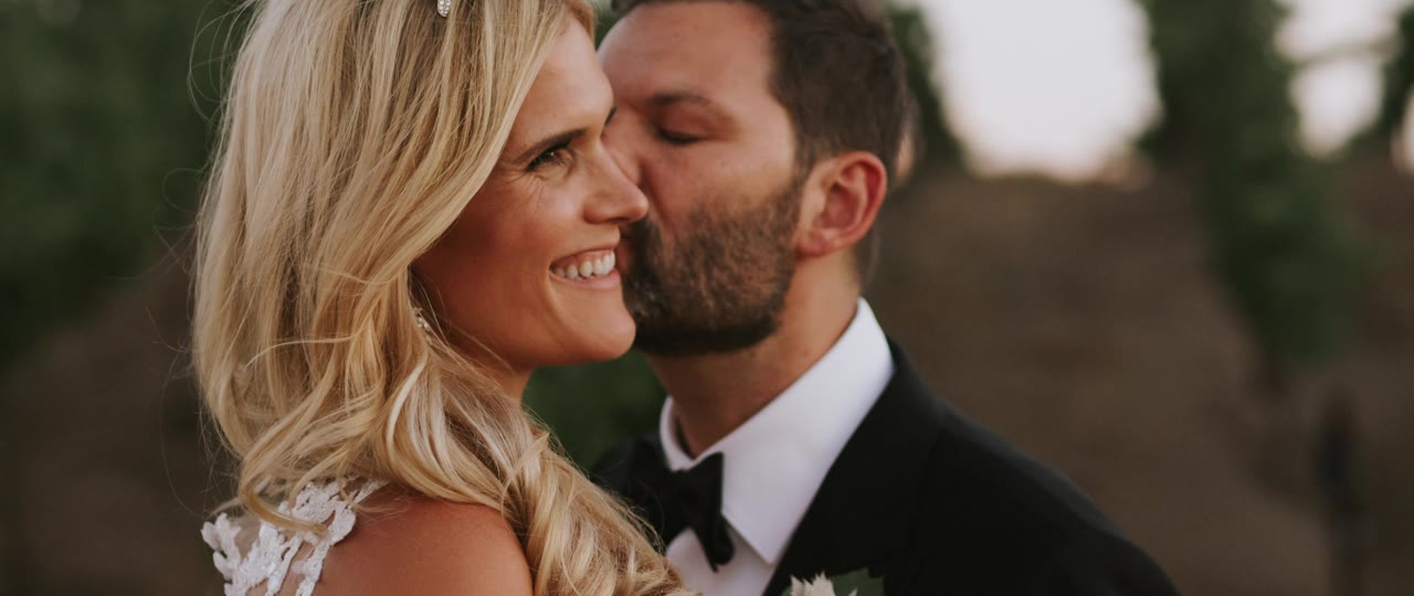 Eric kissing Analise's cheek at golden hour in the vineyard rows at Callaway Vineyard and Winery in Temecula