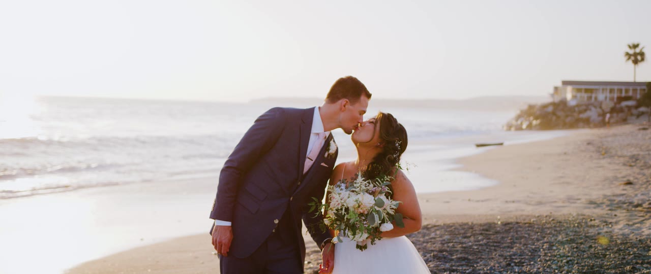 Eric kissing Esther on the sand at golden hour on the San Clemente coast