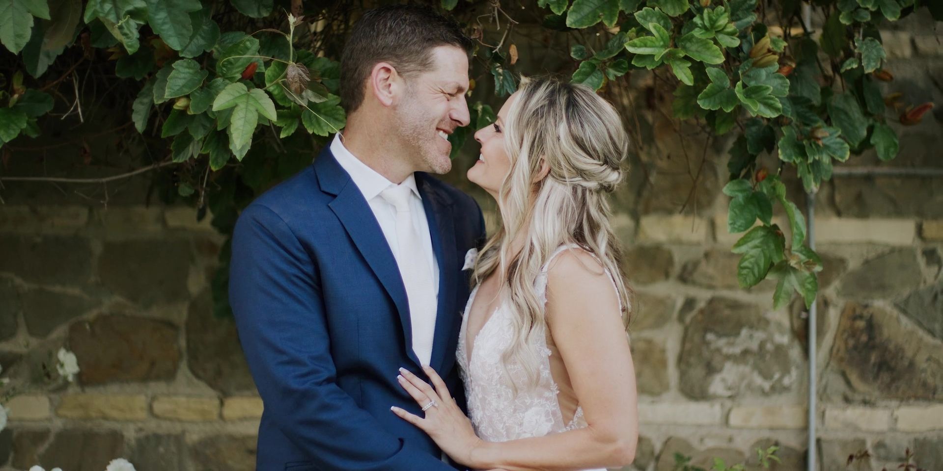 Justin and Mimi smiling at each other against a vine-covered stone wall at the Bel-Air Bay Club