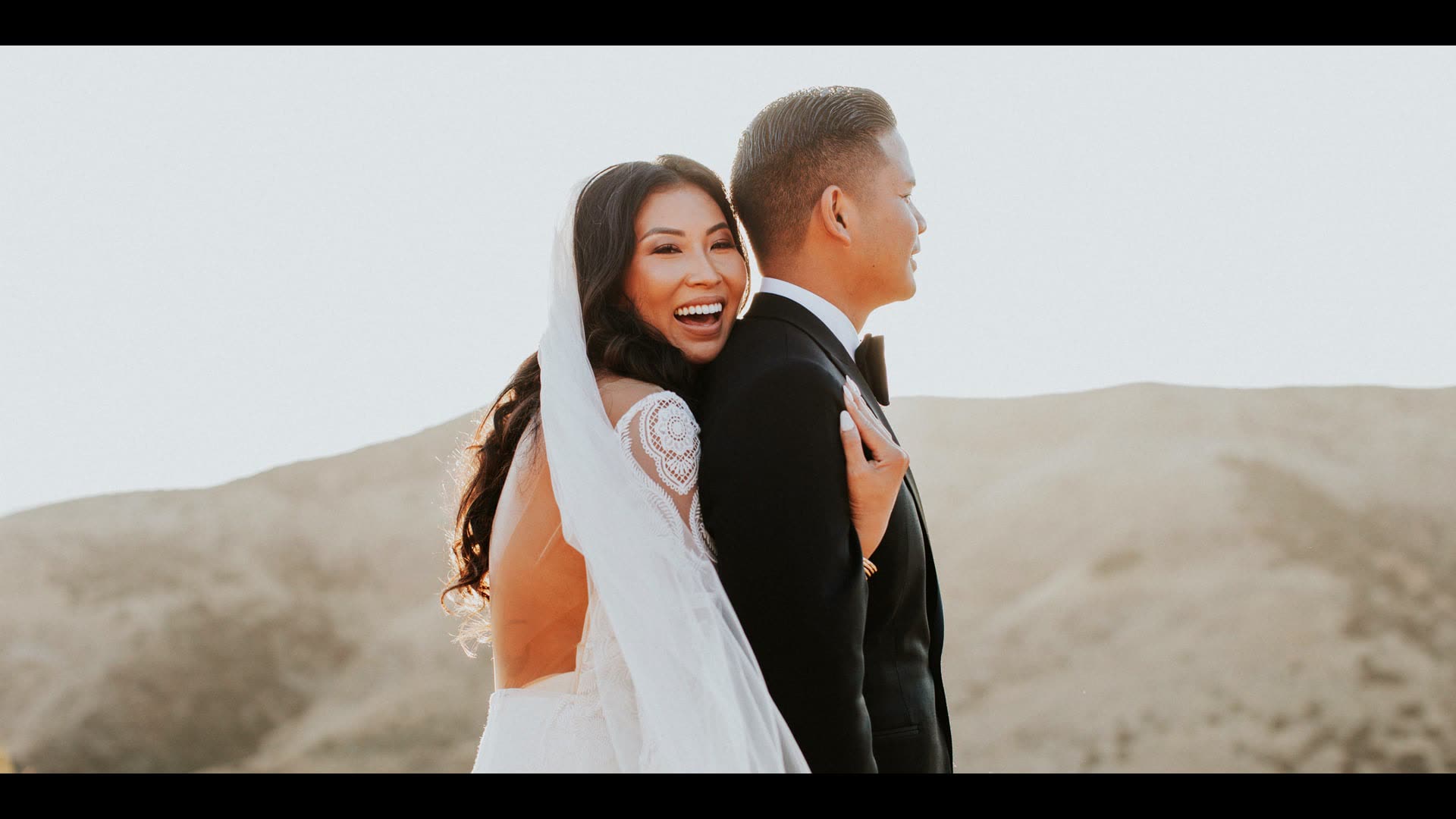 Melvin and An on the pale hillside at Hummingbird Nest Ranch, her veil lifting in the wind