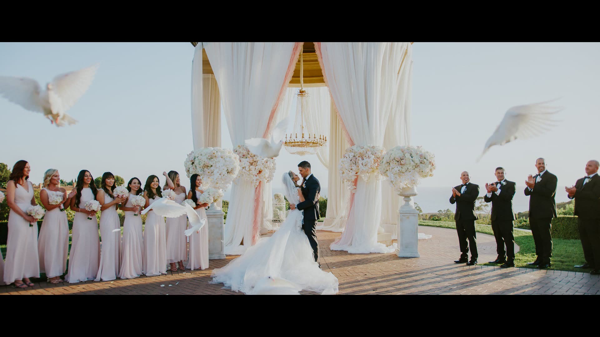 Doves released over Randy and Denise as they marry beneath the draped arch at Pelican Hill