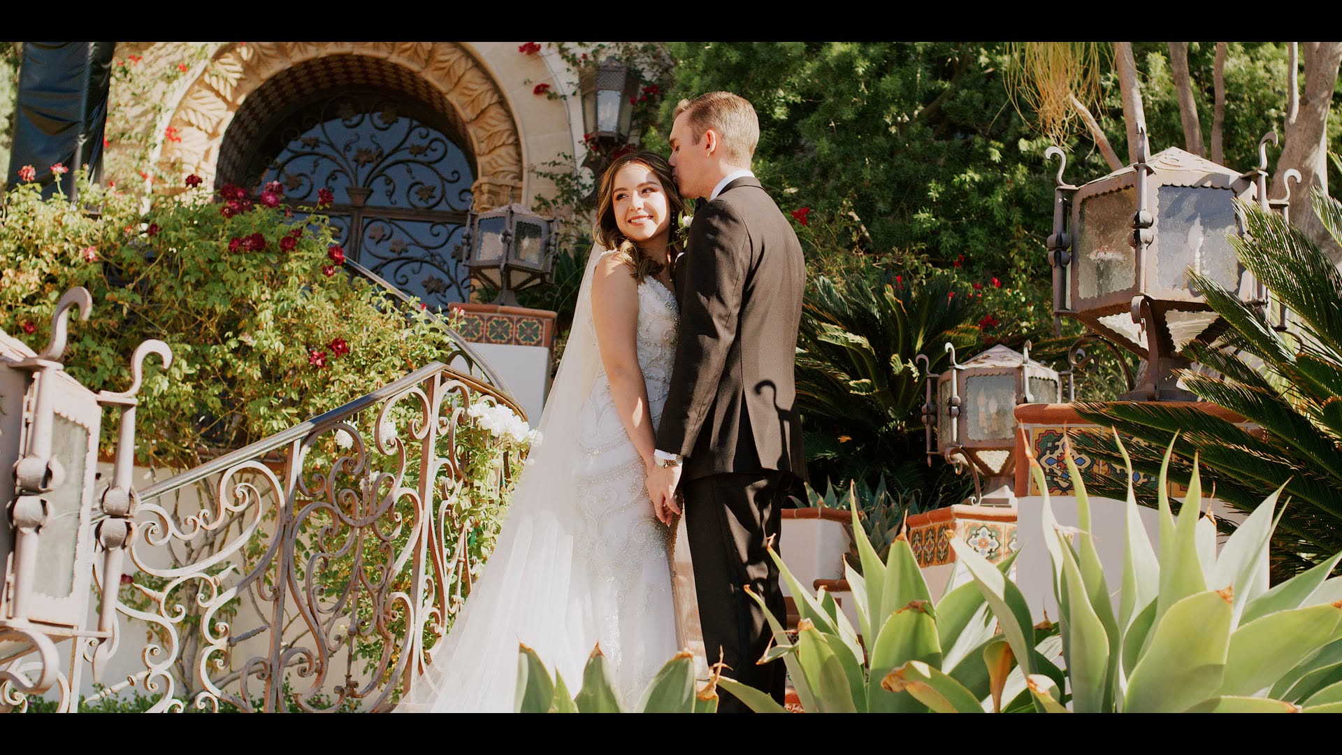 Ryan and Cynthia beside the ironwork gate and bougainvillea at Hummingbird Nest Ranch