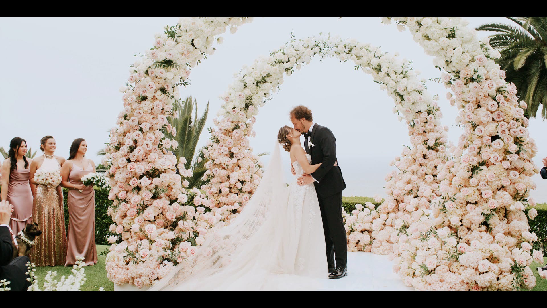 Tanner and Michelle marrying beneath a full floral arch on the lawn at Bel-Air Bay Club