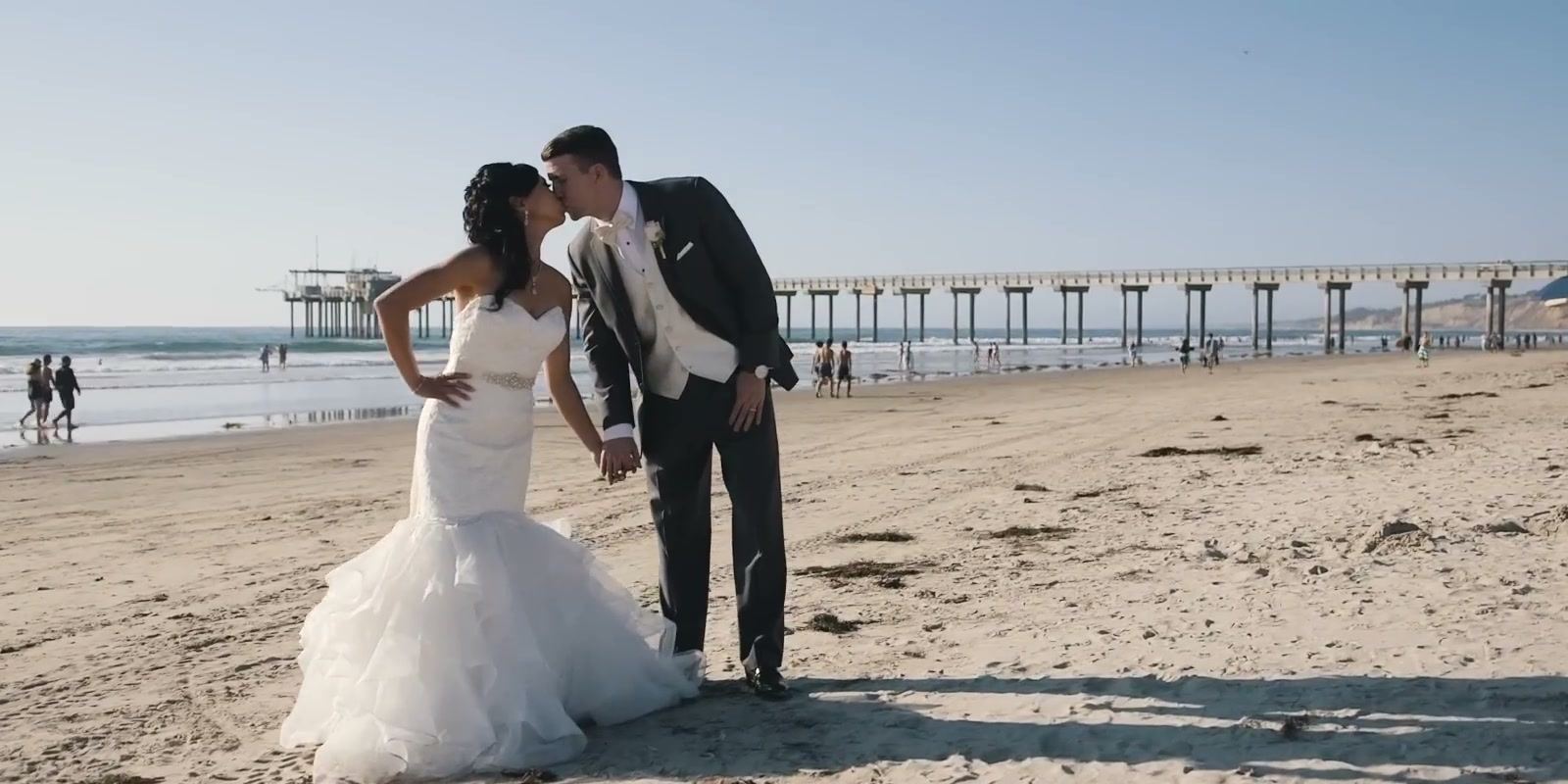 Gina and Jeff kissing on the beach, Scripps Pier stretching out behind them.