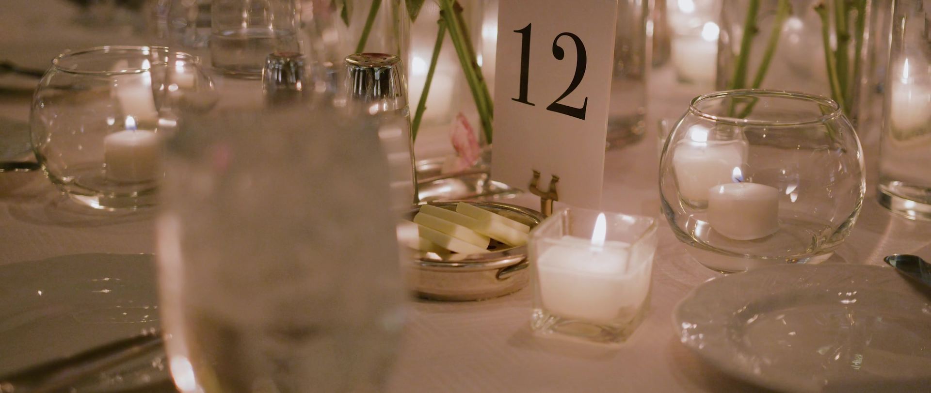 A table number and glass votives set among low candlelight.