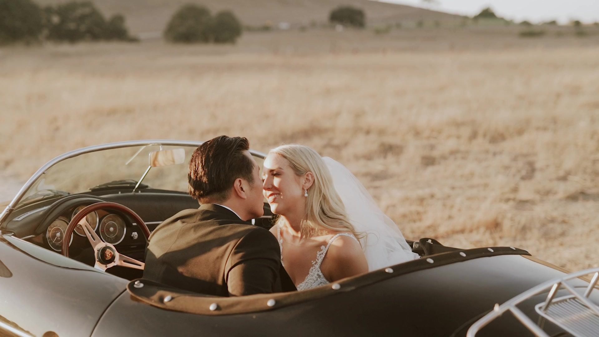 Hyden and Alyson in an open vintage convertible, parked in the dry golden grass at Kestrel Park.