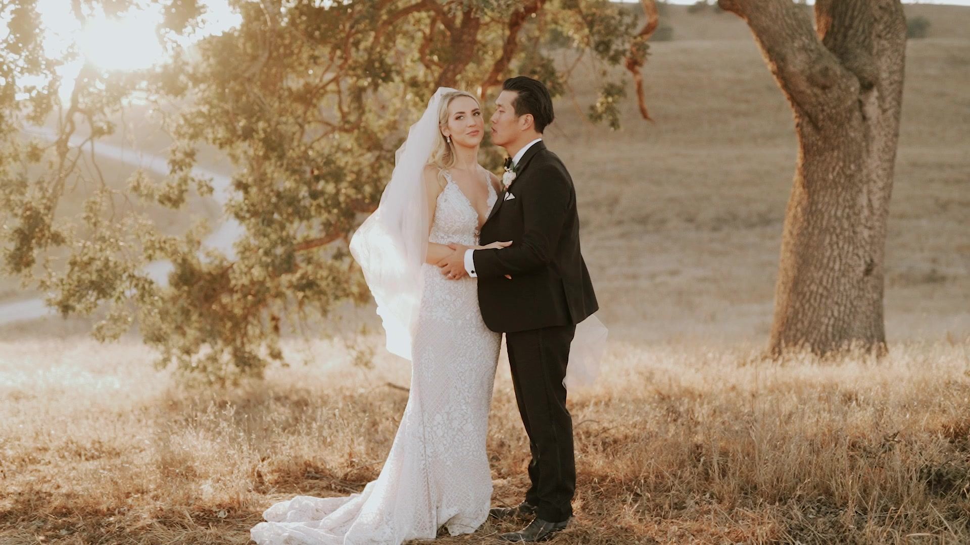Hyden and Alyson together under an oak in the dry golden grass, her veil trailing behind her.