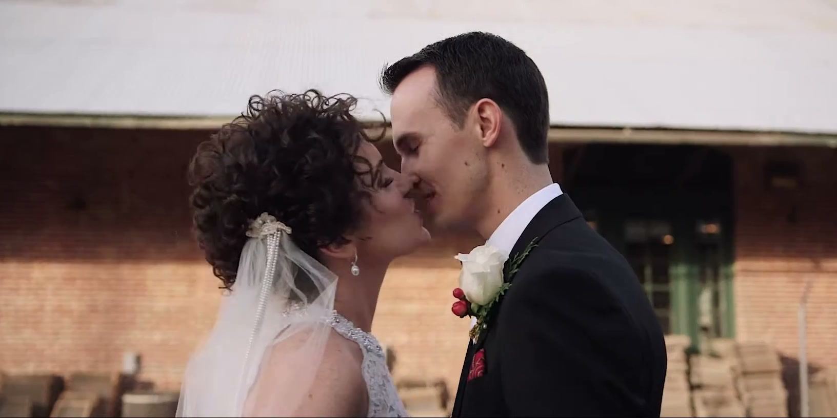 Hayley and Brandon close to a kiss in front of the brick building.