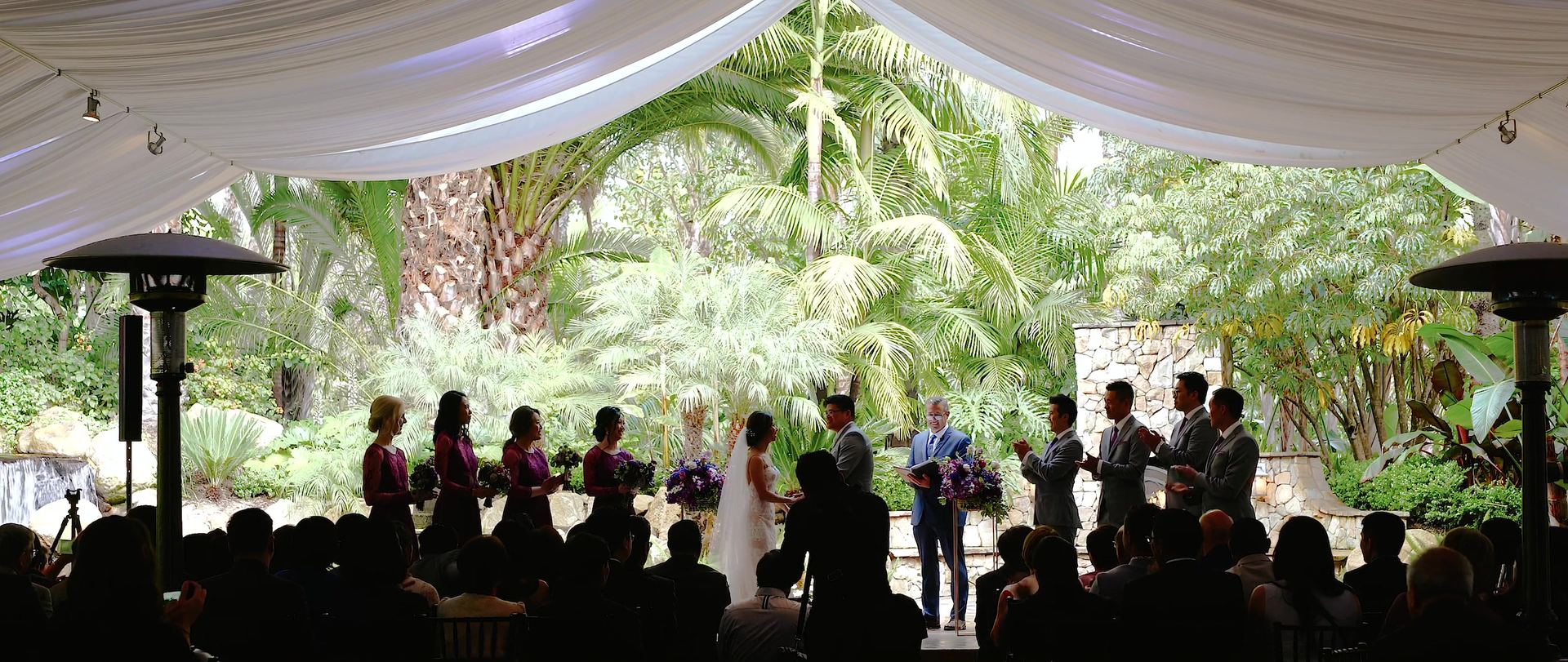 The ceremony under a white canopy at Grand Tradition Estate, guests seated with palms and gardens all around.