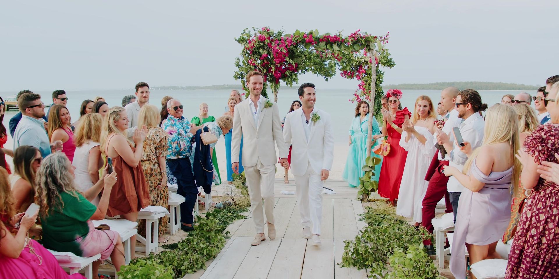 Coming back down the aisle after the ceremony, guests cheering on both sides.
