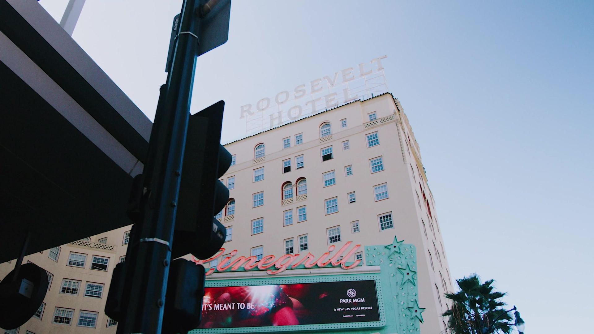 The Roosevelt's rooftop sign against a clear blue sky, a traffic signal in the foreground and the marquee below.