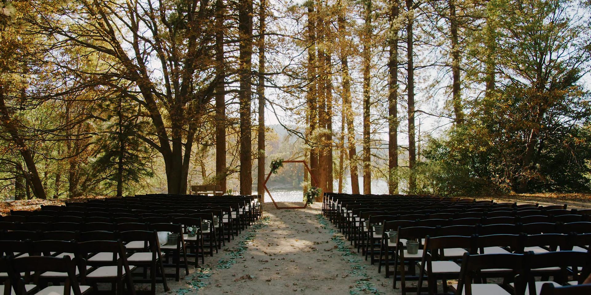 The ceremony set among the pines at San Moritz Lodge, rows of chairs facing the lake.