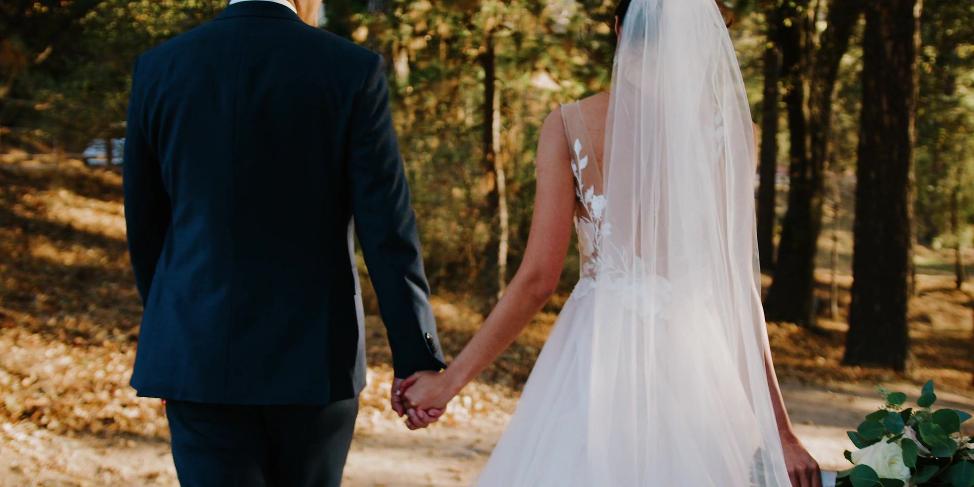 Jonathan and April walking hand in hand through the pines.