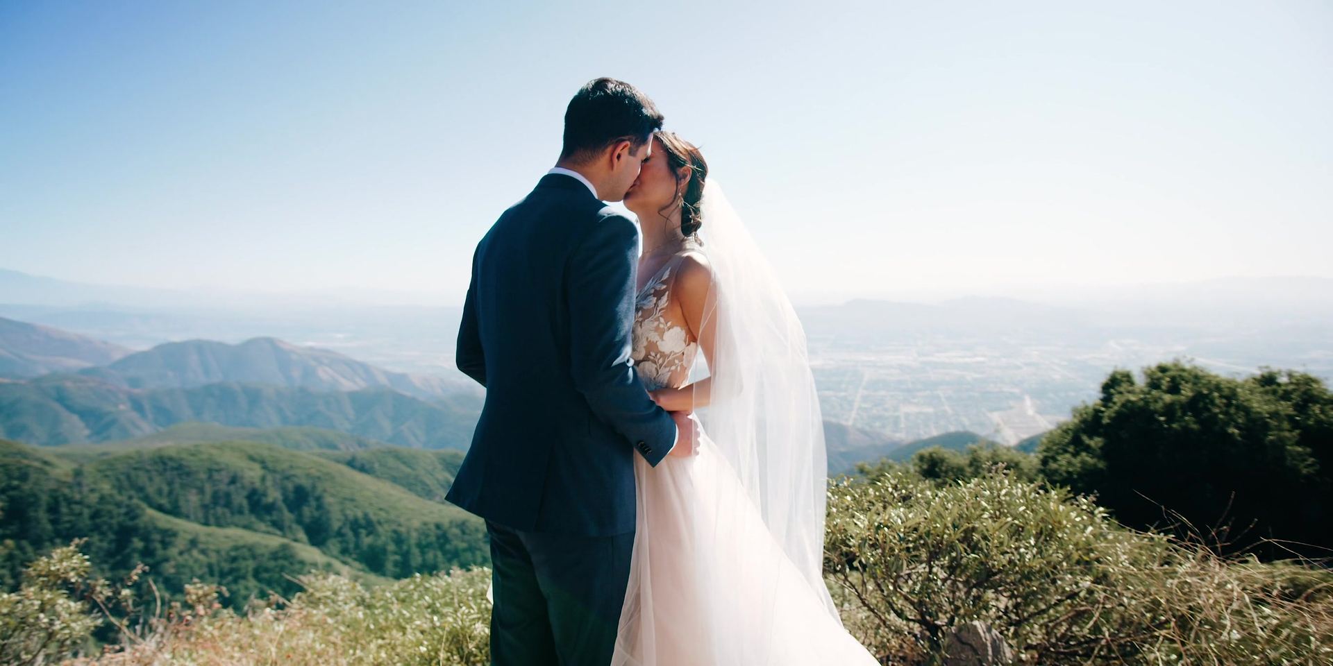 Jonathan and April kissing with the mountain valley opening up behind them.
