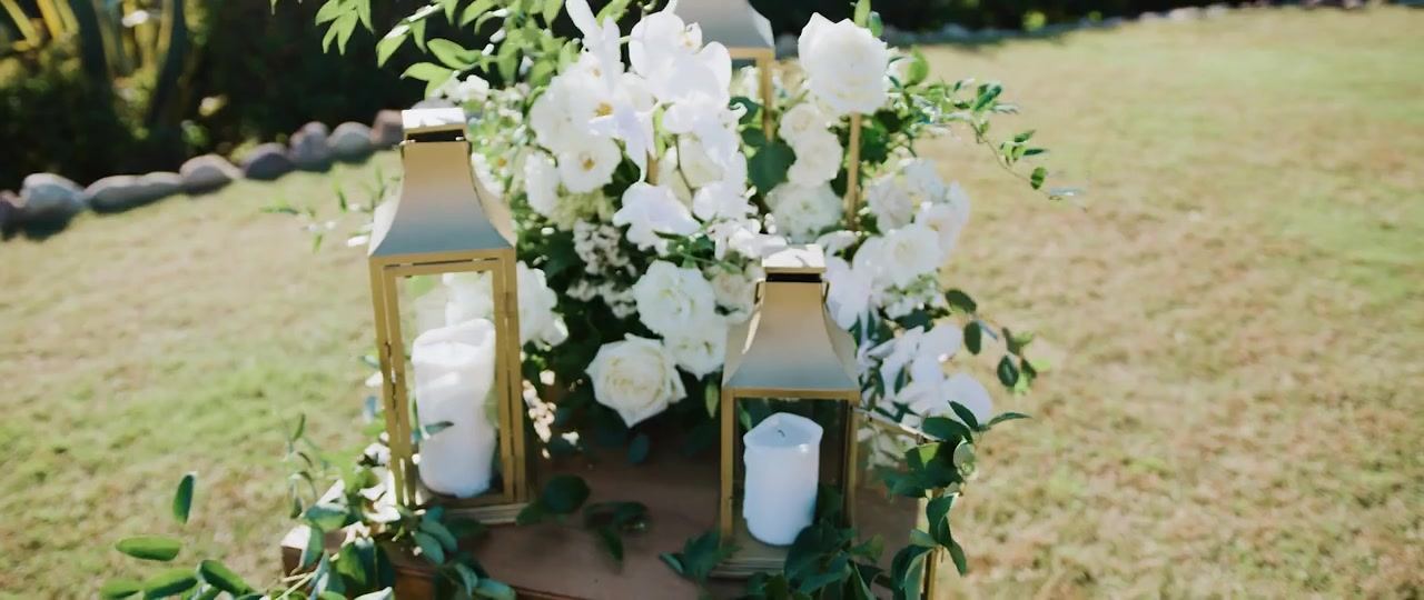 White roses and orchids with gold lanterns set out on the lawn.